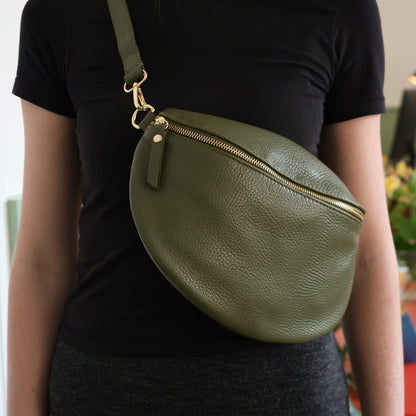Person wearing a green leather crossbody bag indoors