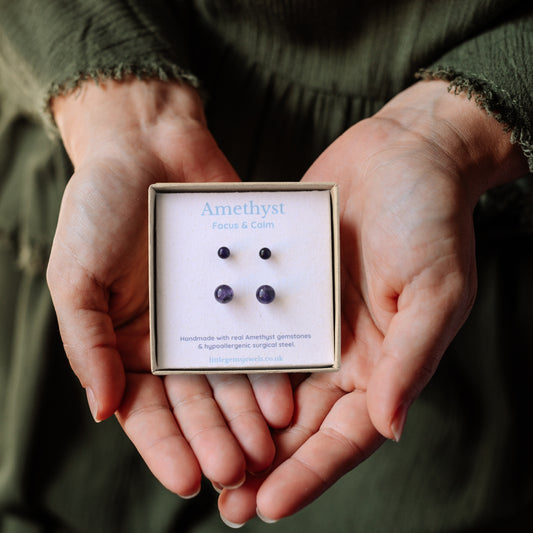 Hands holding a box of Amethyst earrings with a blurred background