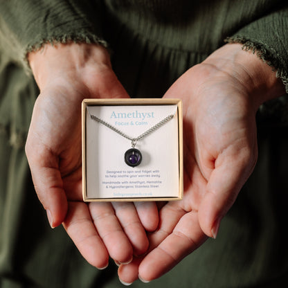 Amethyst gemstone spinner necklace in a gift box being held in a woman's hands.