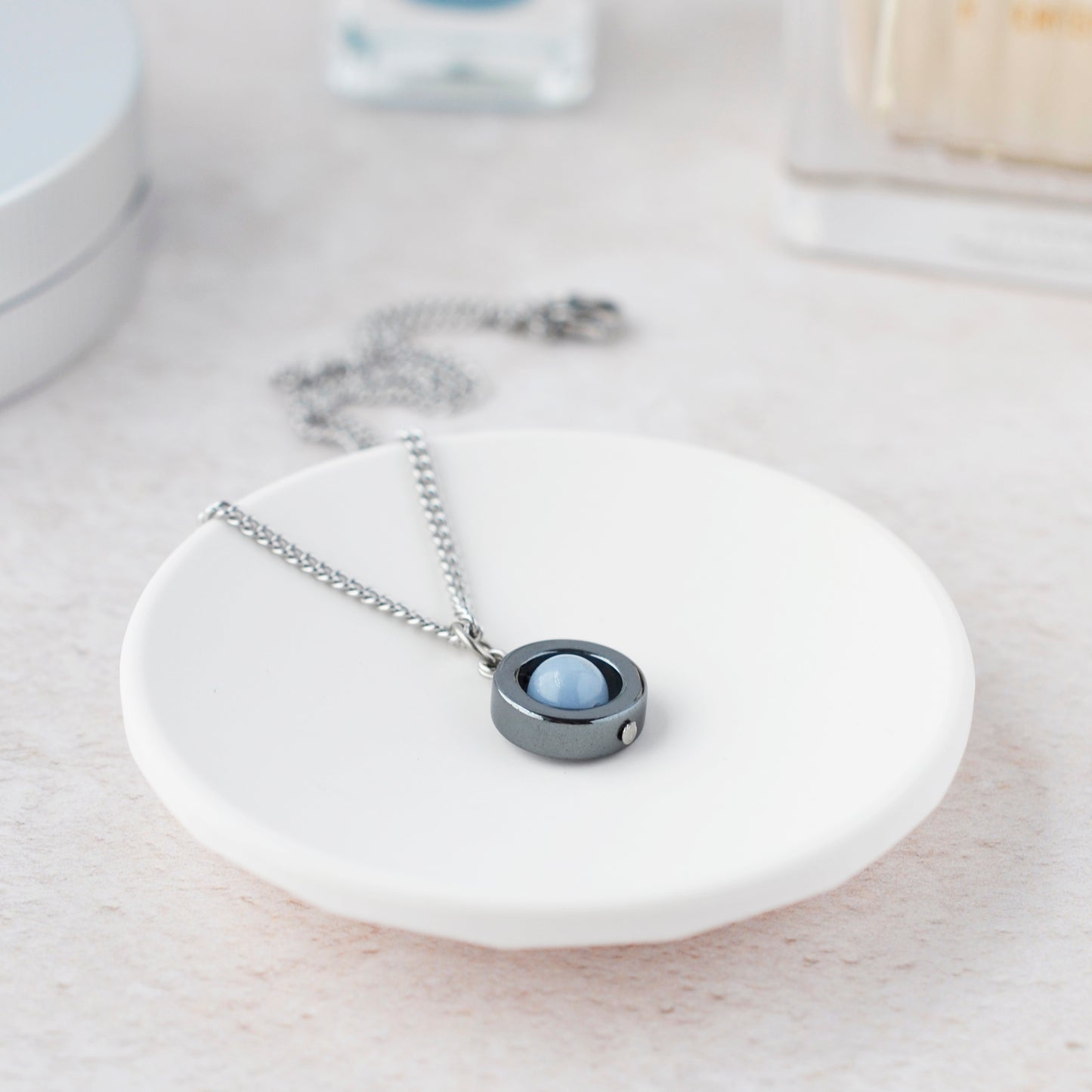 Angelite spinner necklace laying in white trinket dish.