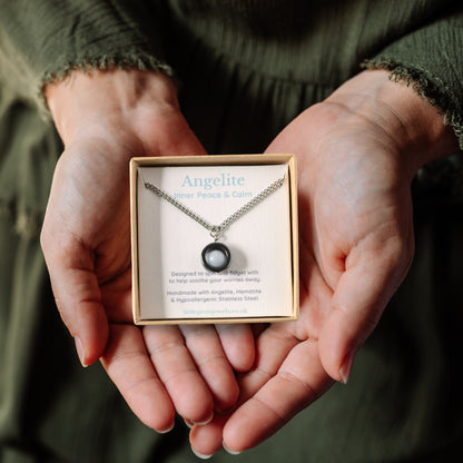 Angelite gemstone spinner necklace in a gift box being held in a woman's hands.