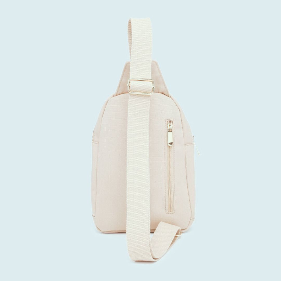 Side view of beige sling bag on a light blue background