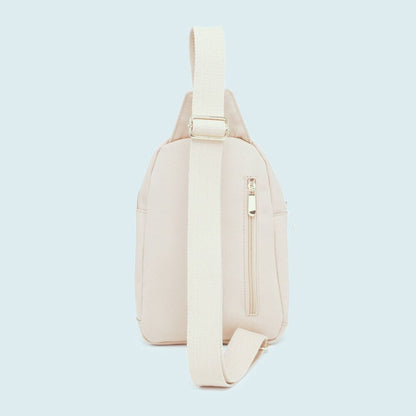 Side view of beige sling bag on a light blue background