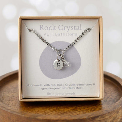 Rock Crystal April Birthstone necklace with hand stamped initial inside an eco-friendly gift box sitting on wooden coaster