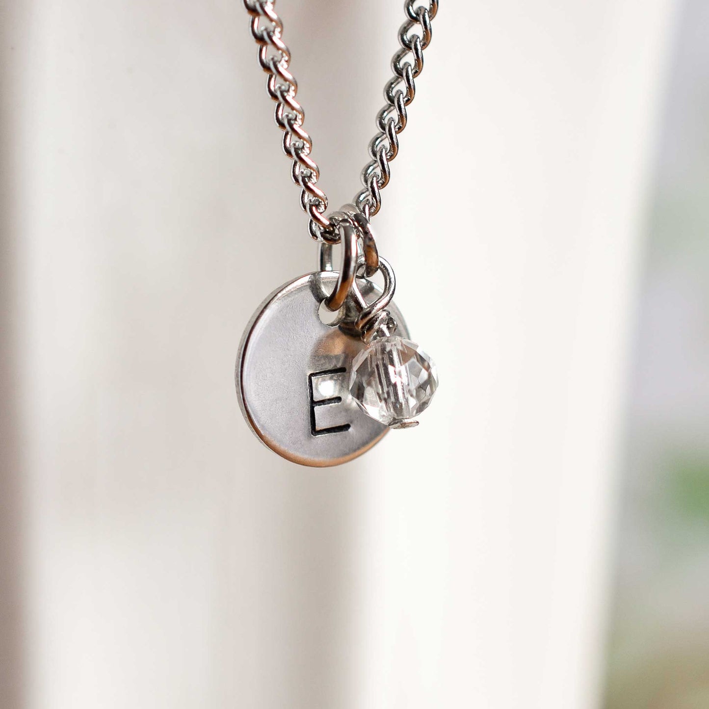 Close up of letter E initial pendant with April birthstone charm