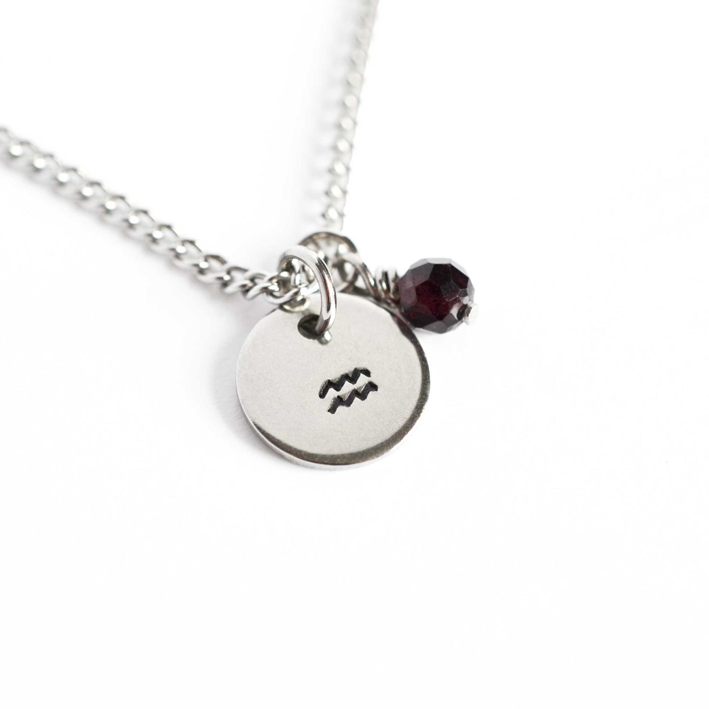 Aquarius Zodiac pendant necklace with tiny Garnet gemstone charm on white background