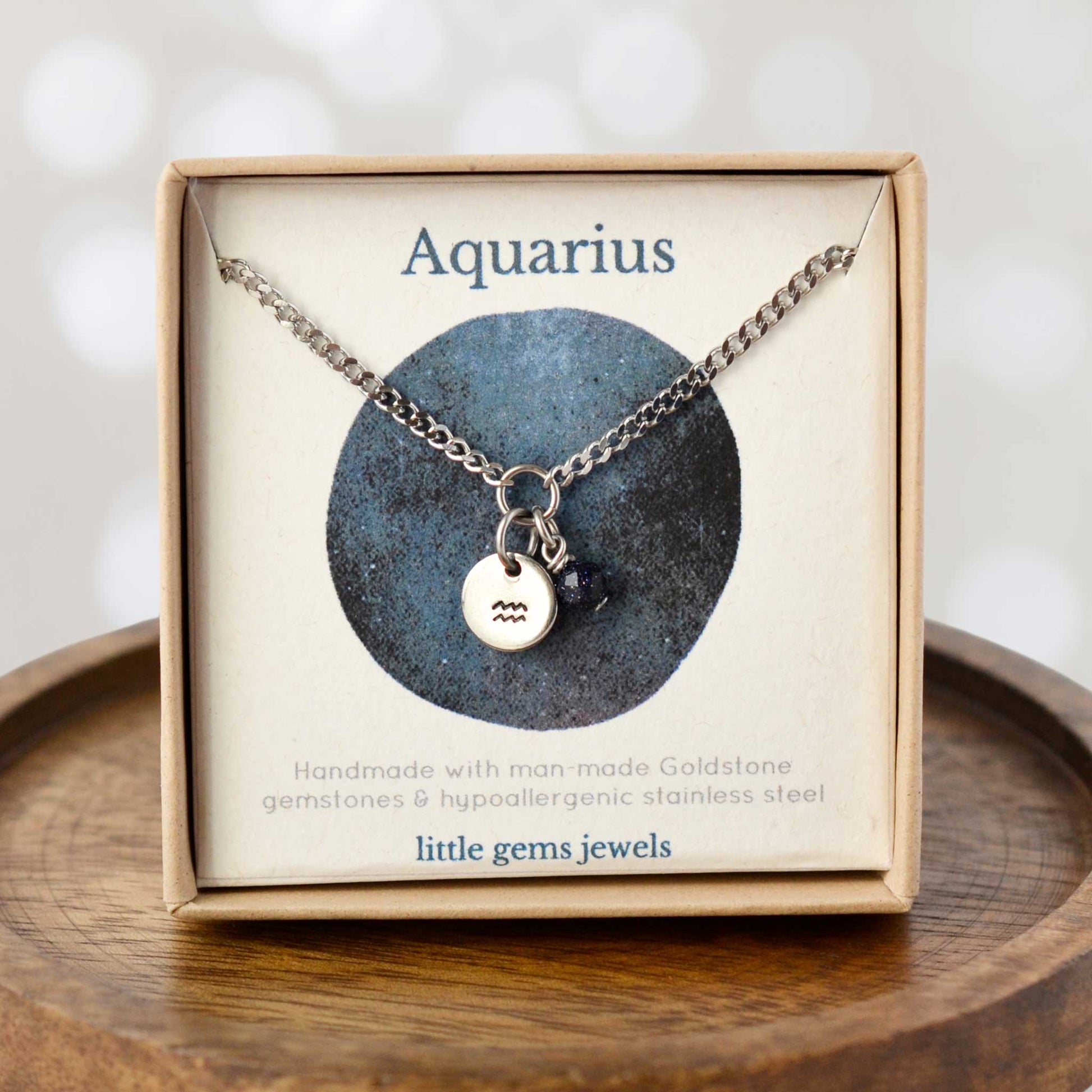 Dainty Aquarius zodiac sign necklace in eco-friendly gift box on wooden coaster