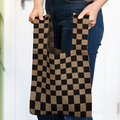 Person holding a checkered brown and black reusable bag.