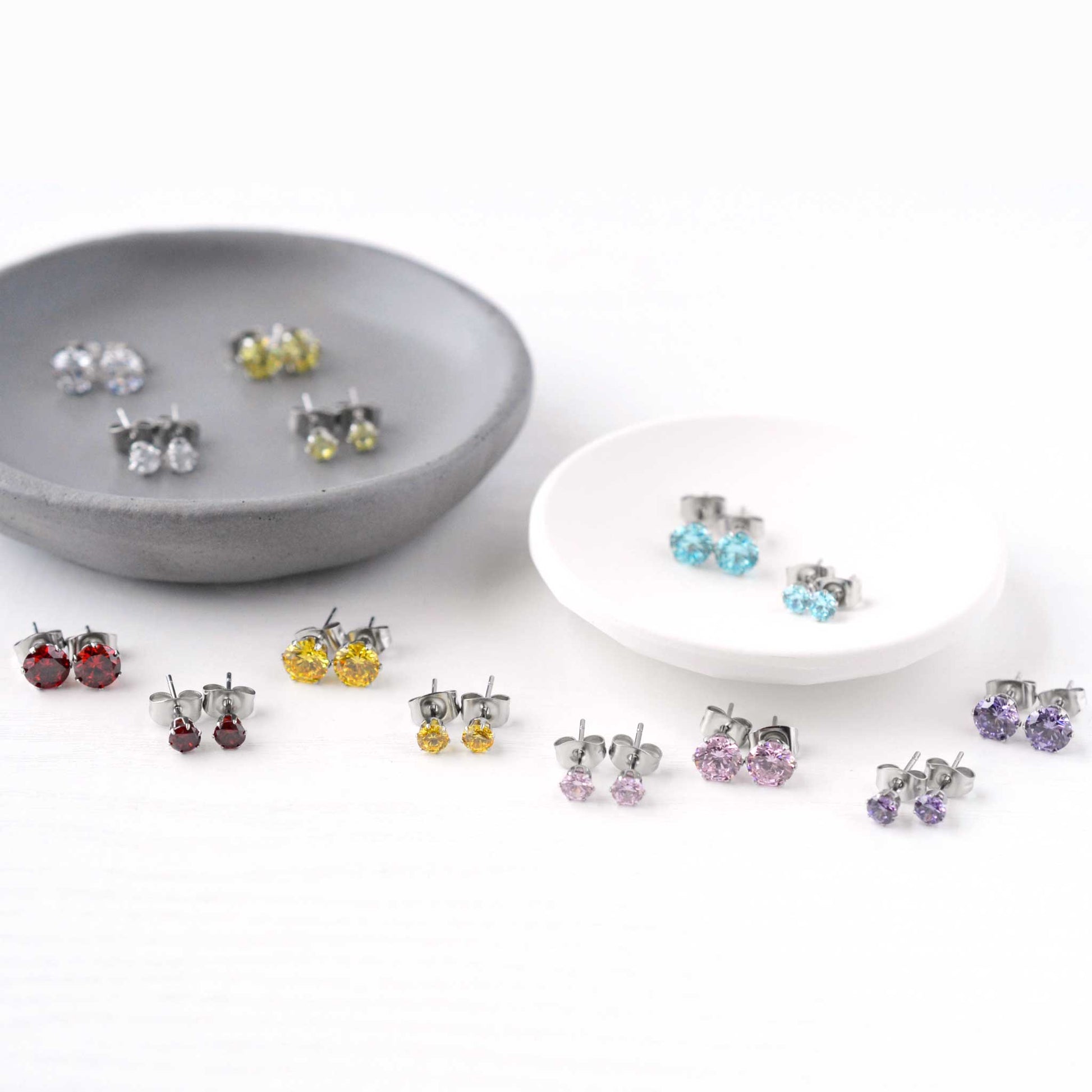 Multi coloured Cubic Zirconia gemstones in trinket dishes on white background