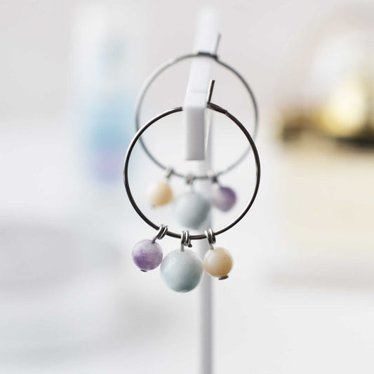 Pastel colour gemstone bead hoop earrings hanging against soft focus background
