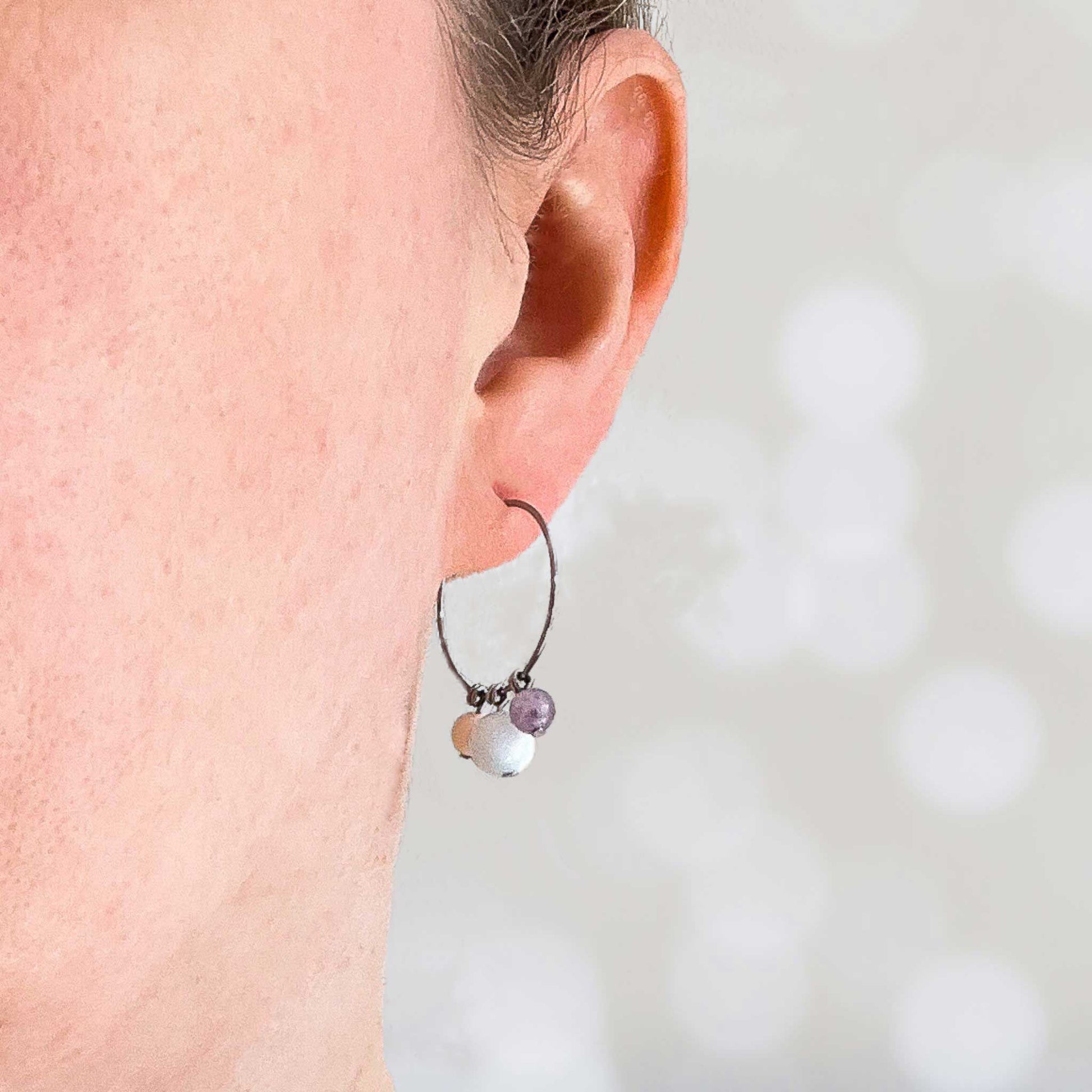 Woman wearing pastel gemstone beaded hoop earring in earlobe