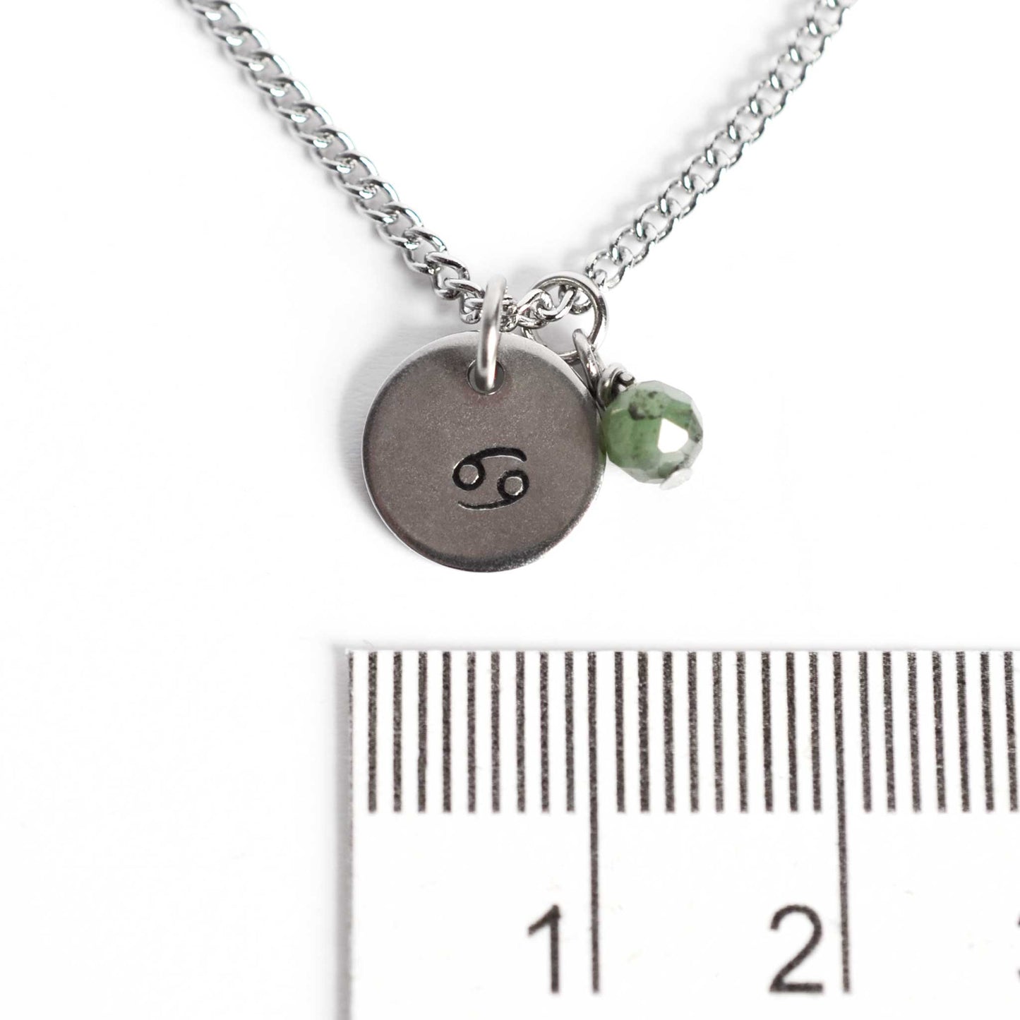 1cm diameter disc pendant with hand stamped Cancer zodiac sign and 4mm Emerald gemstone charm