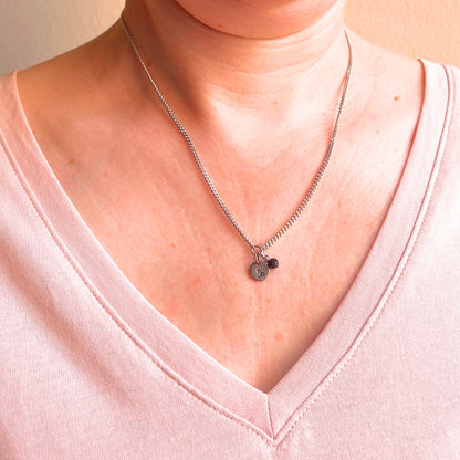 Woman wearing a pink v neck top and dainty Capricorn zodiac sign necklace.