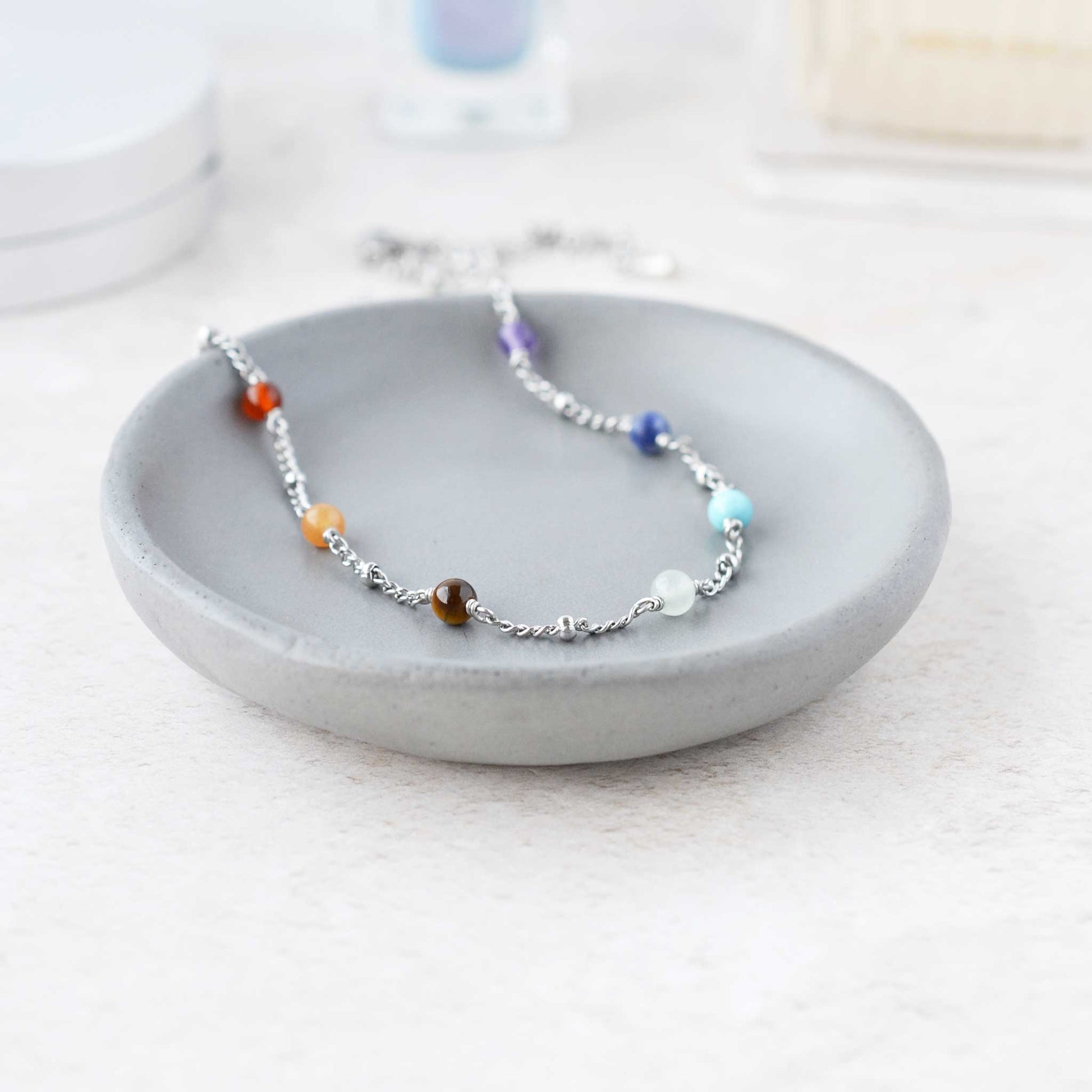 Necklace with colorful beads on a gray dish against a white background
