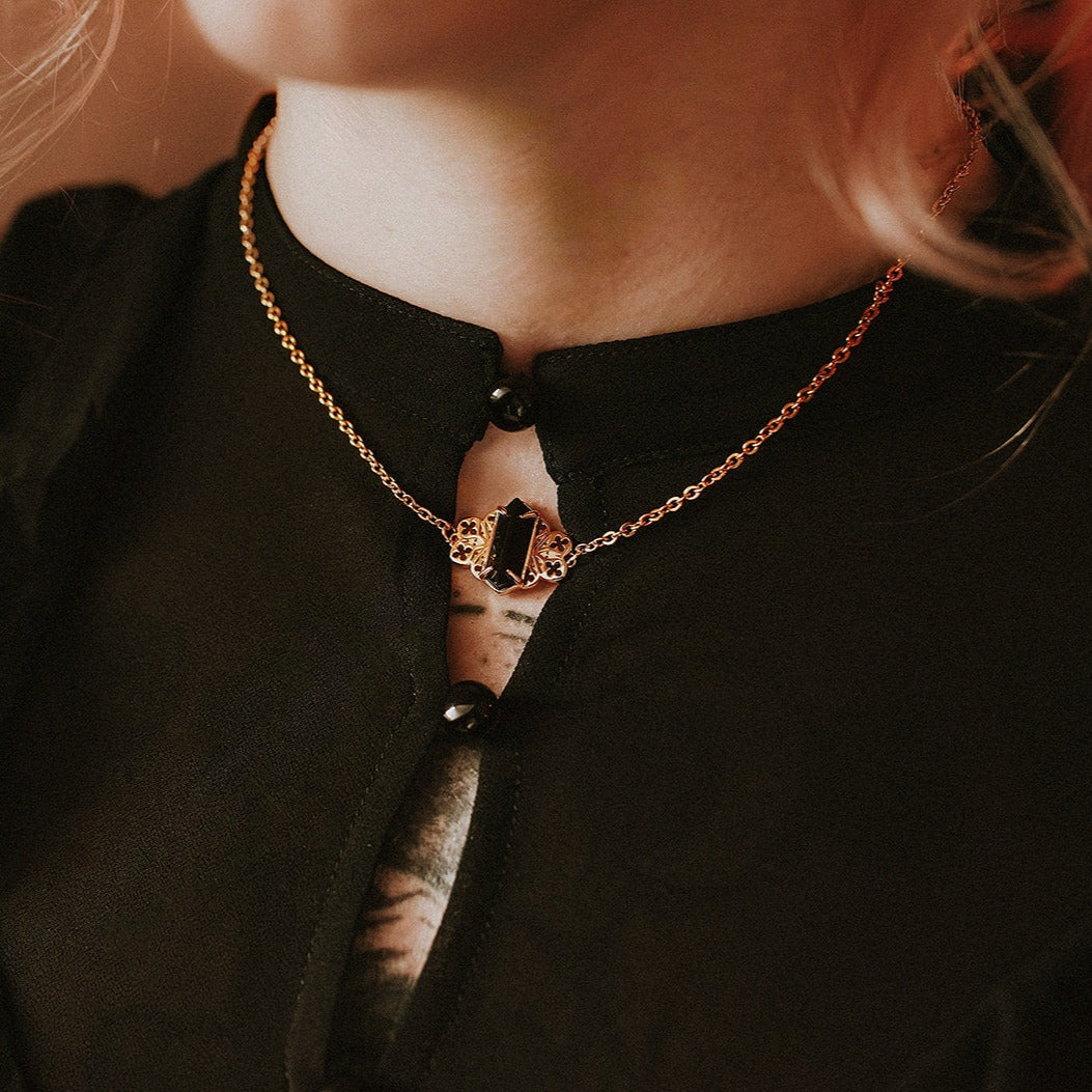 Necklace with a pendant worn by a person against a dark background