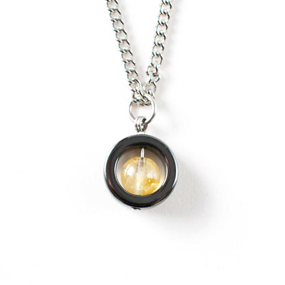 Citrine gemstone fidget spinner necklace on white background.