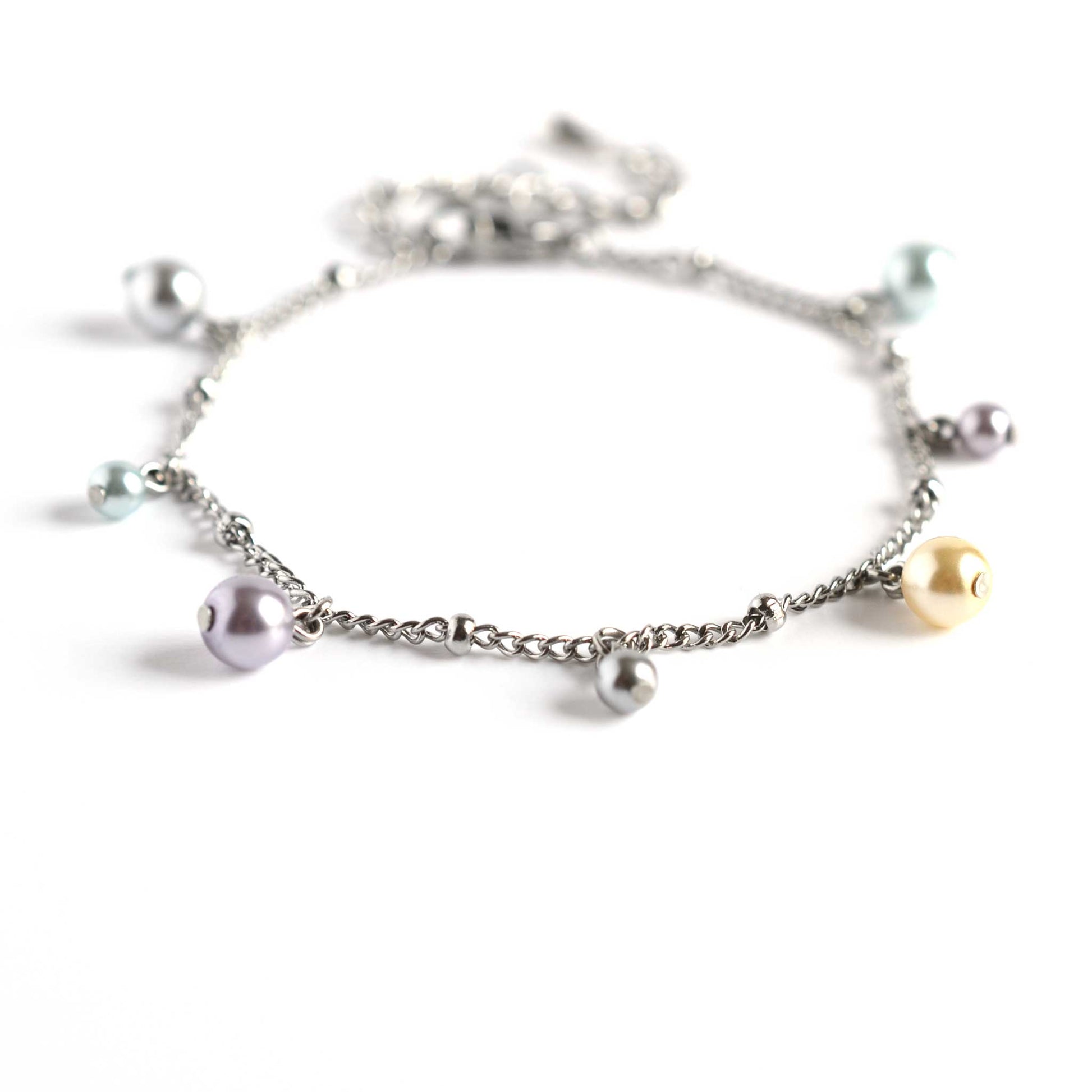 Close up of dainty faux pearl charms bracelet on white background