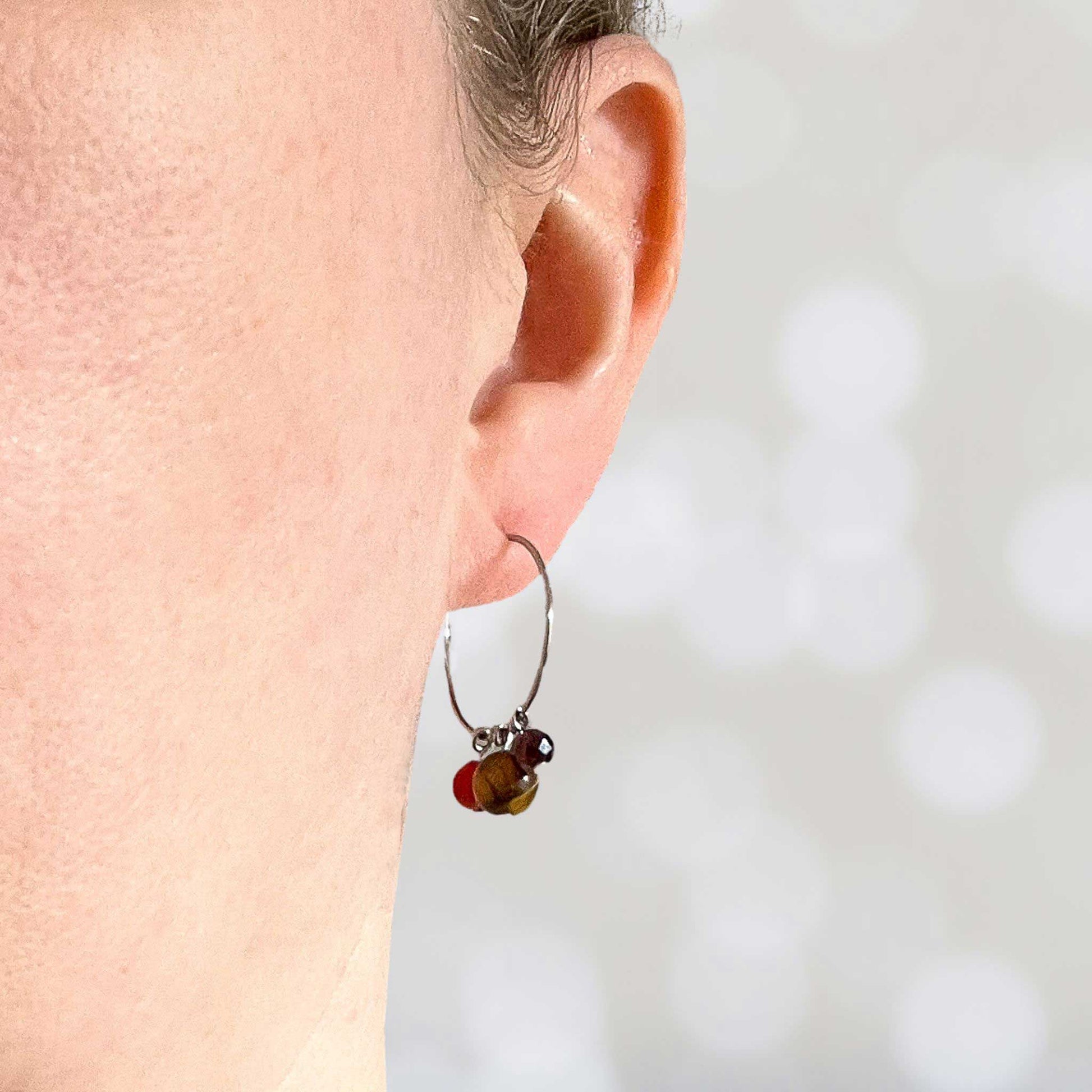 Women wearing dark gemstone hoop earring in earlobe