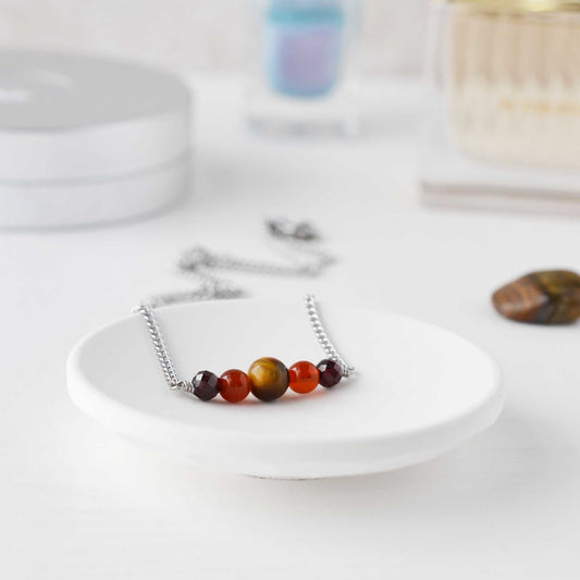 Brown and orange dainty gemstone necklace in trinket dish on dressing table