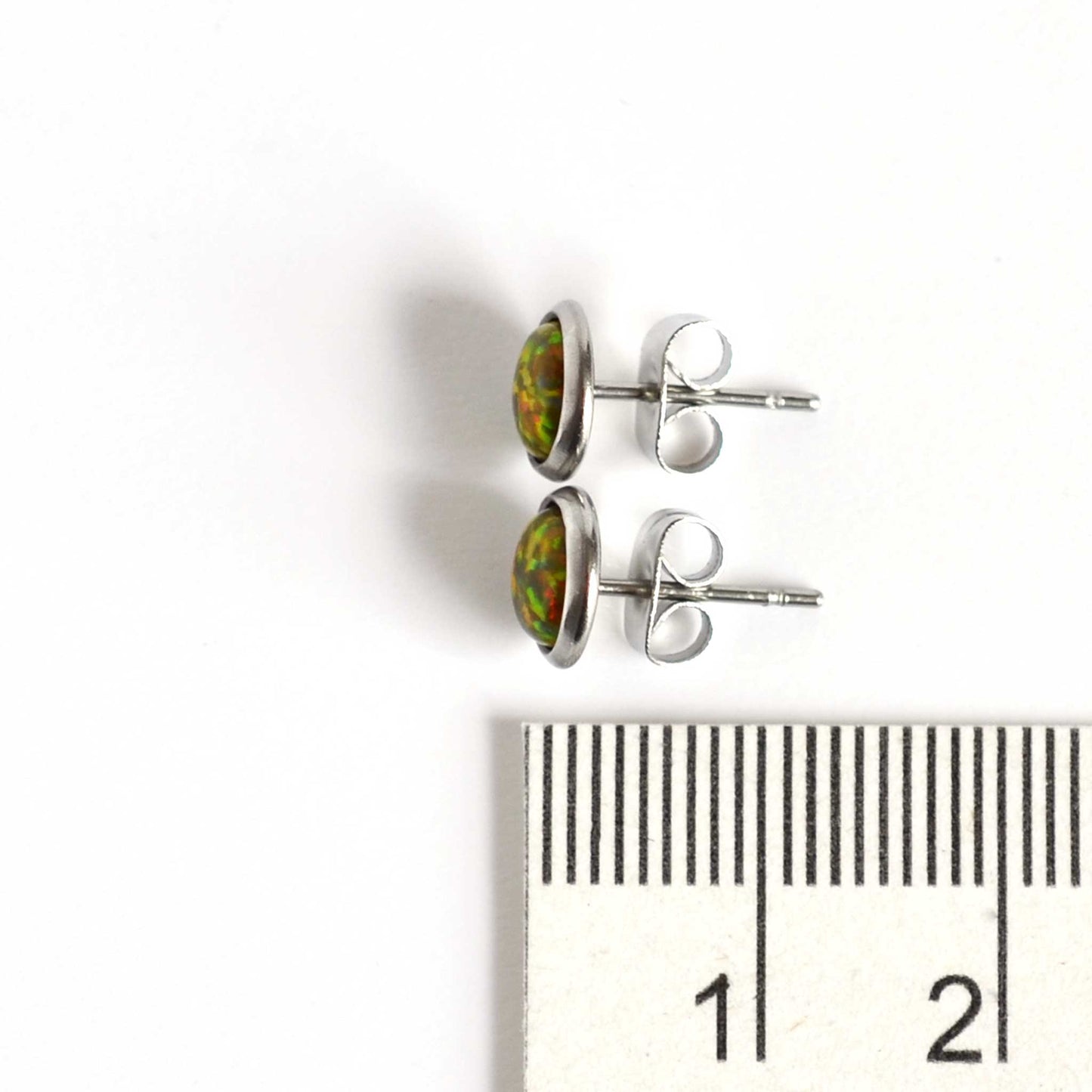 Dark green Opal stud earrings next to ruler