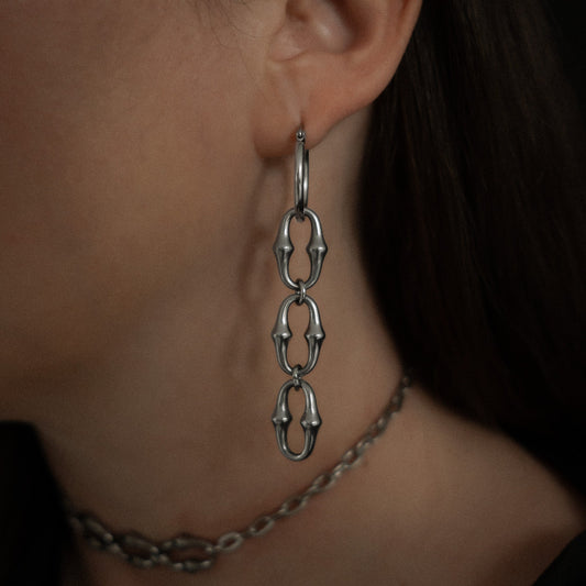 Close-up of a person wearing a steel chain earring.