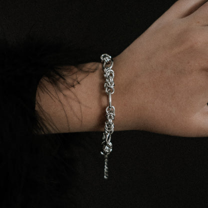 Steel chain bracelet on a wrist against a dark background