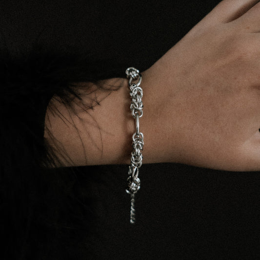 Steel chain bracelet on a wrist against a dark background