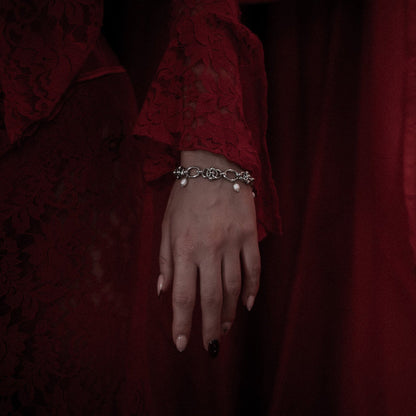 Hand wearing a bracelet with a dark red background