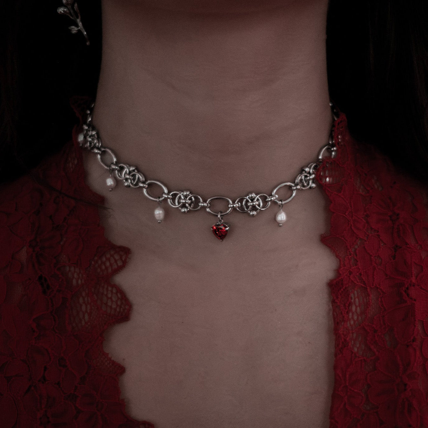 Stainless steel necklace with charms on a person's neck against a dark background