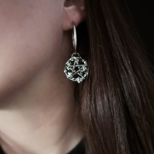 Close-up of a steel earring with a star design worn by a person.