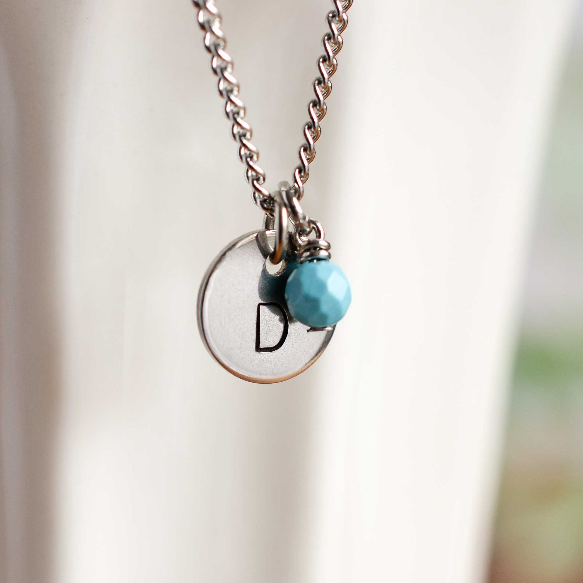 Close up of letter D disc initial pendant with Turquoise December birthstone charm