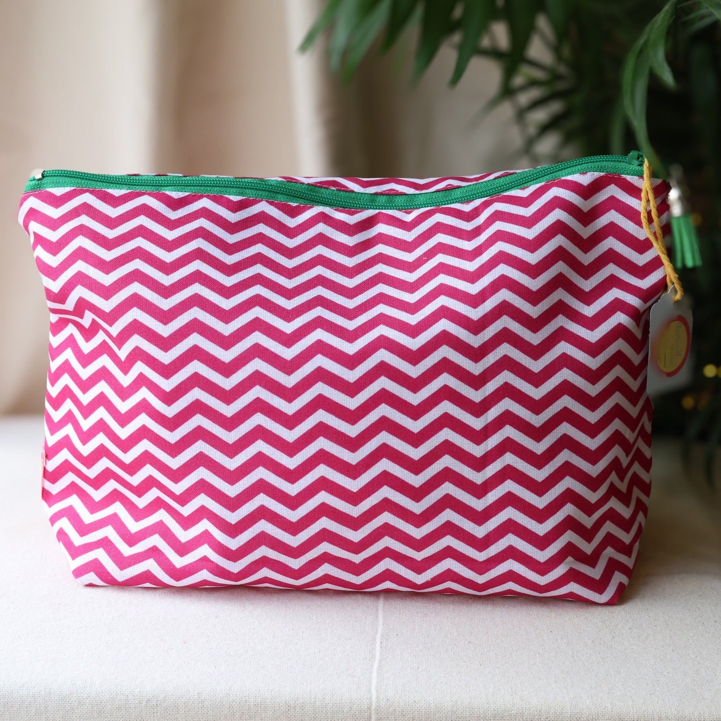Pink and white chevron patterned pouch with green zipper on a beige surface.