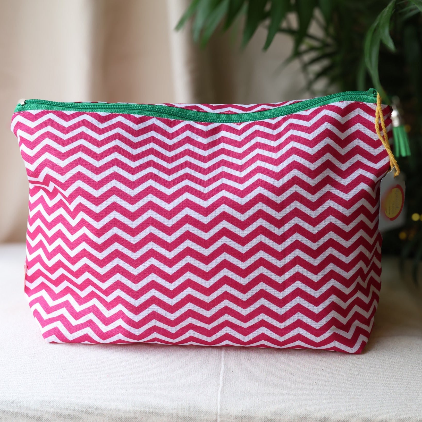 Pink and white chevron patterned pouch with green zipper on a beige surface.