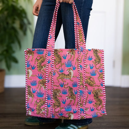 Person holding a pink tote bag with tiger pattern indoors