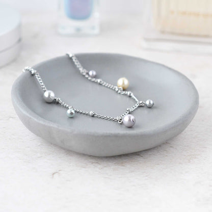Dainty faux pearl charms bracelet in grey trinket dish on dressing table.