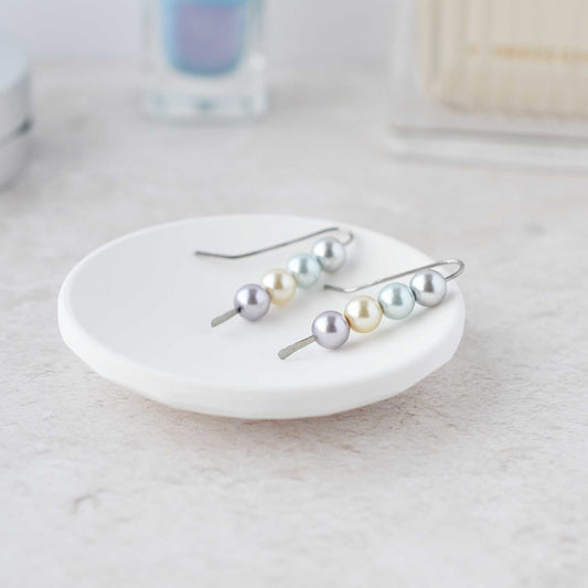 Pastel pearl stack earrings lying in white trinket dish.