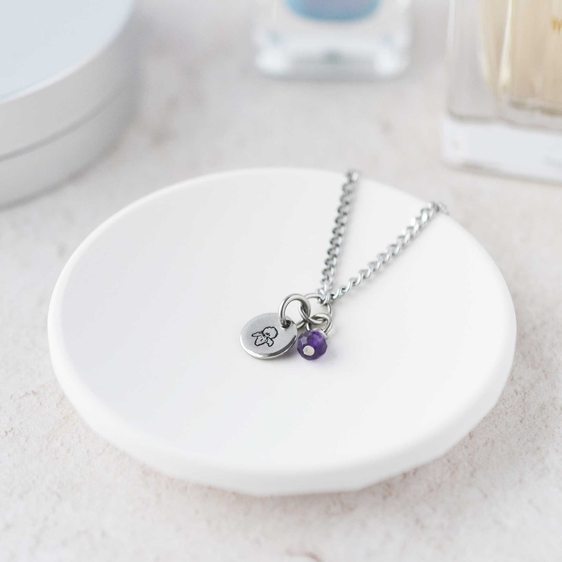 Tiny Violet & Amethyst gemstone necklace laying in white trinket dish