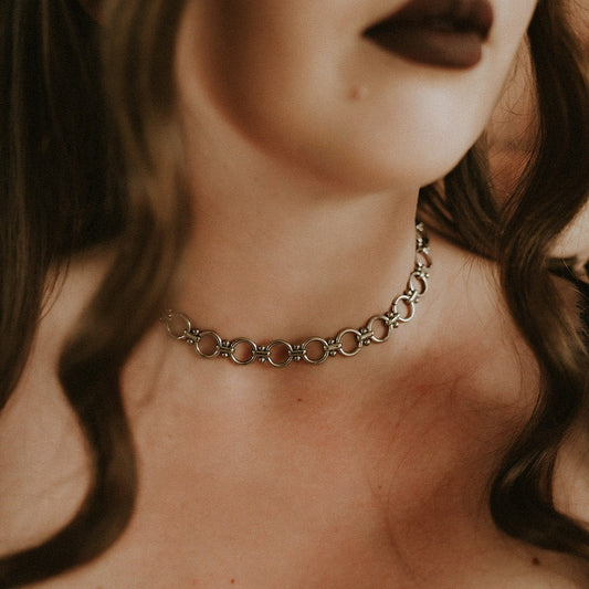 Close-up of a person wearing a chain necklace with a blurred background