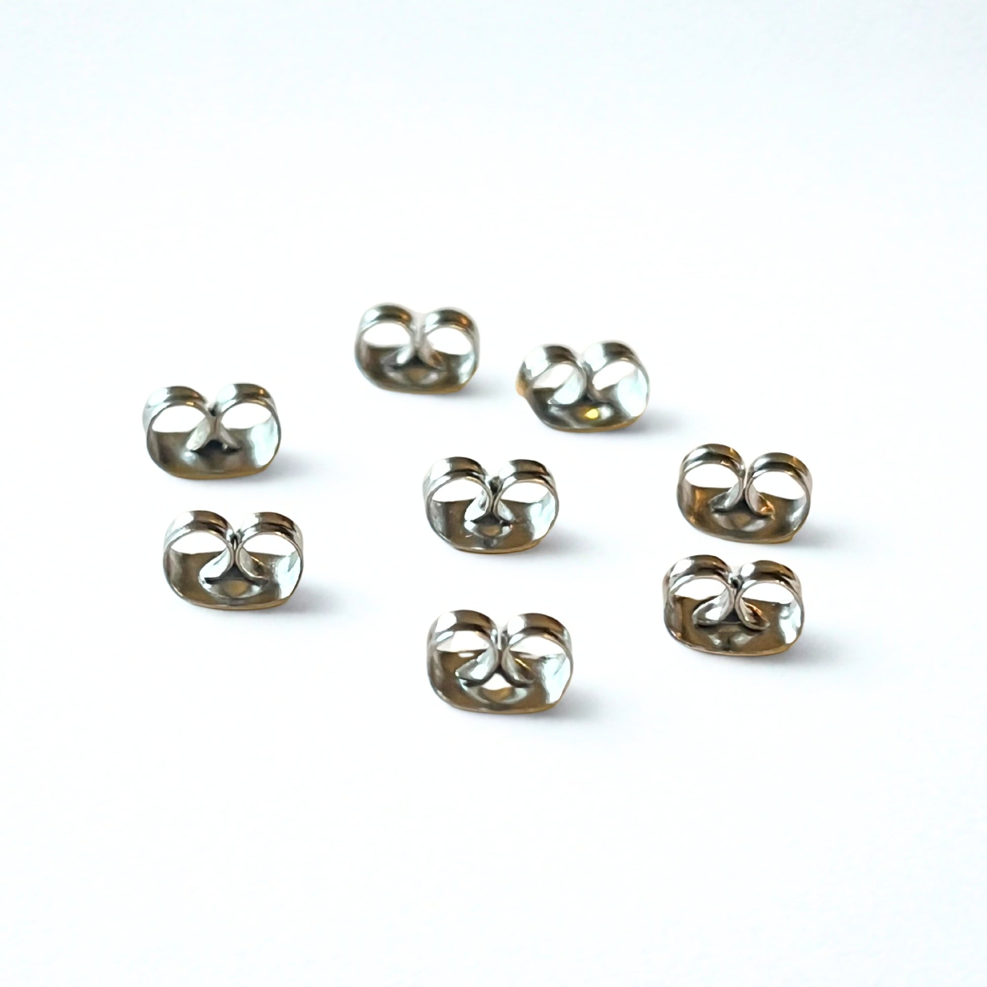 Set of eight surgical steel butterfly earring backs on a white background