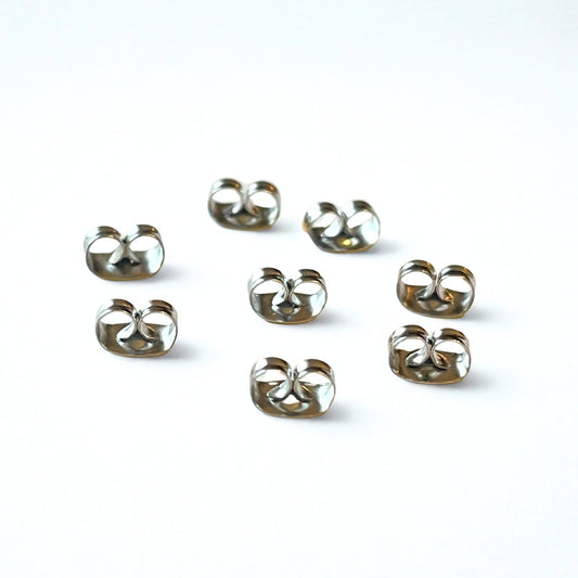 Set of eight surgical steel butterfly earring backs on a white background