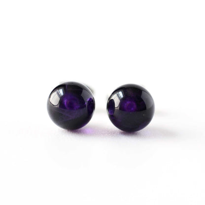 Front view pair of purple round earrings on a white background