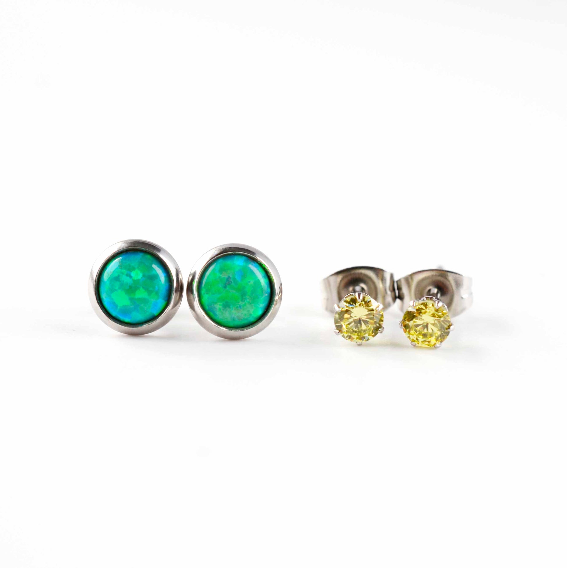 Front view of green lab opal studs and green CZ stud earrings on white background.