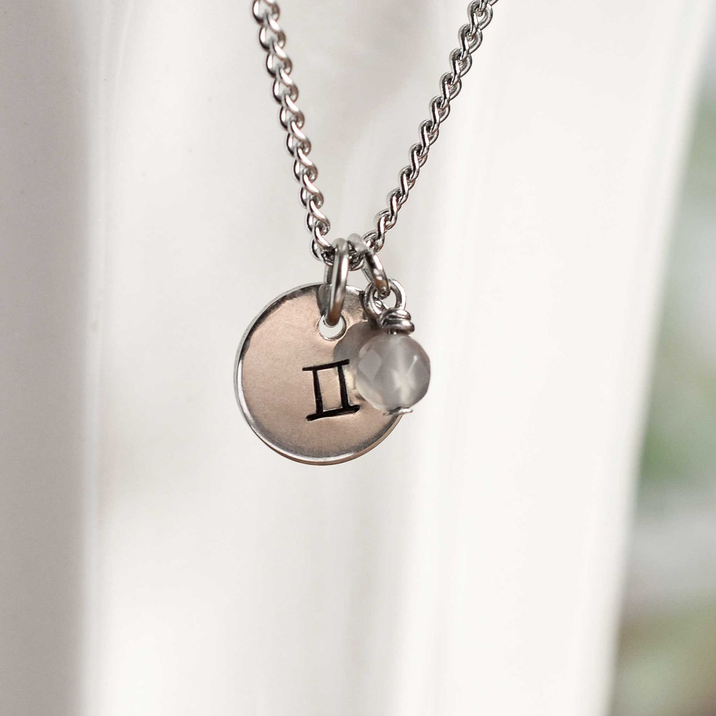 Close up of Gemini zodiac sign necklace with Agate gemstone charm on stainless steel chain