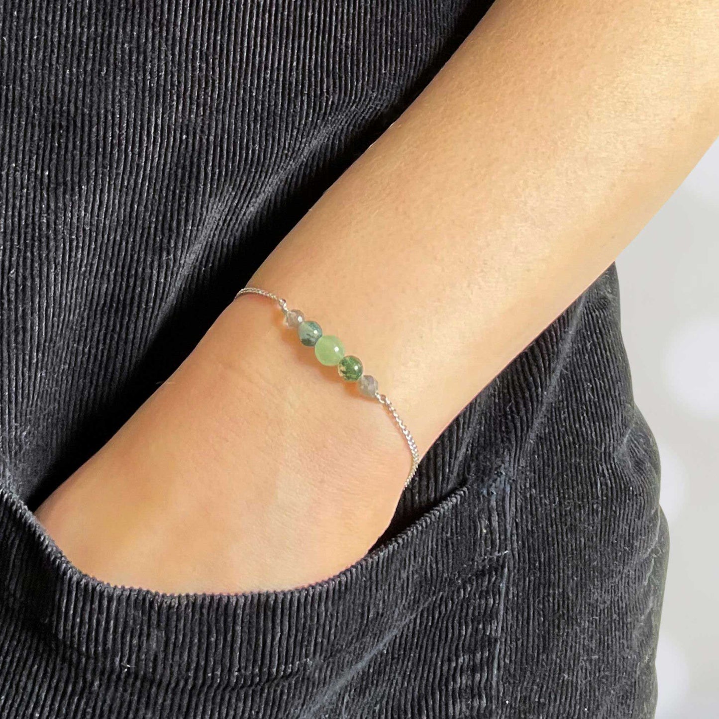 Woman with hand in pocket wearing green gemstone bracelet