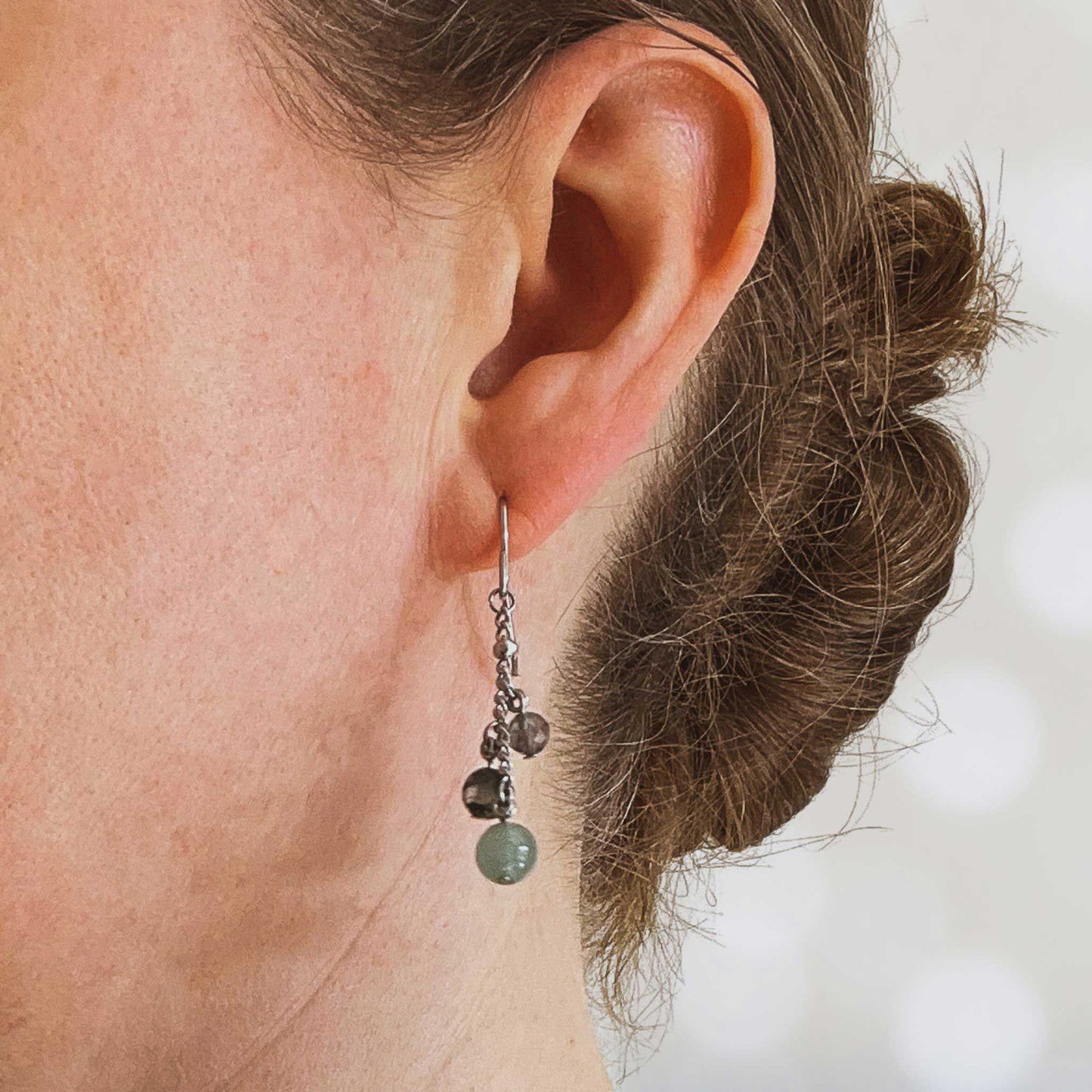 Woman wearing green gemstone drop earring in earlobe