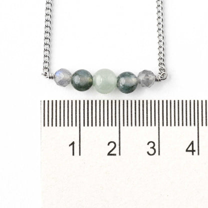 Dainty green gemstone bracelet next to ruler