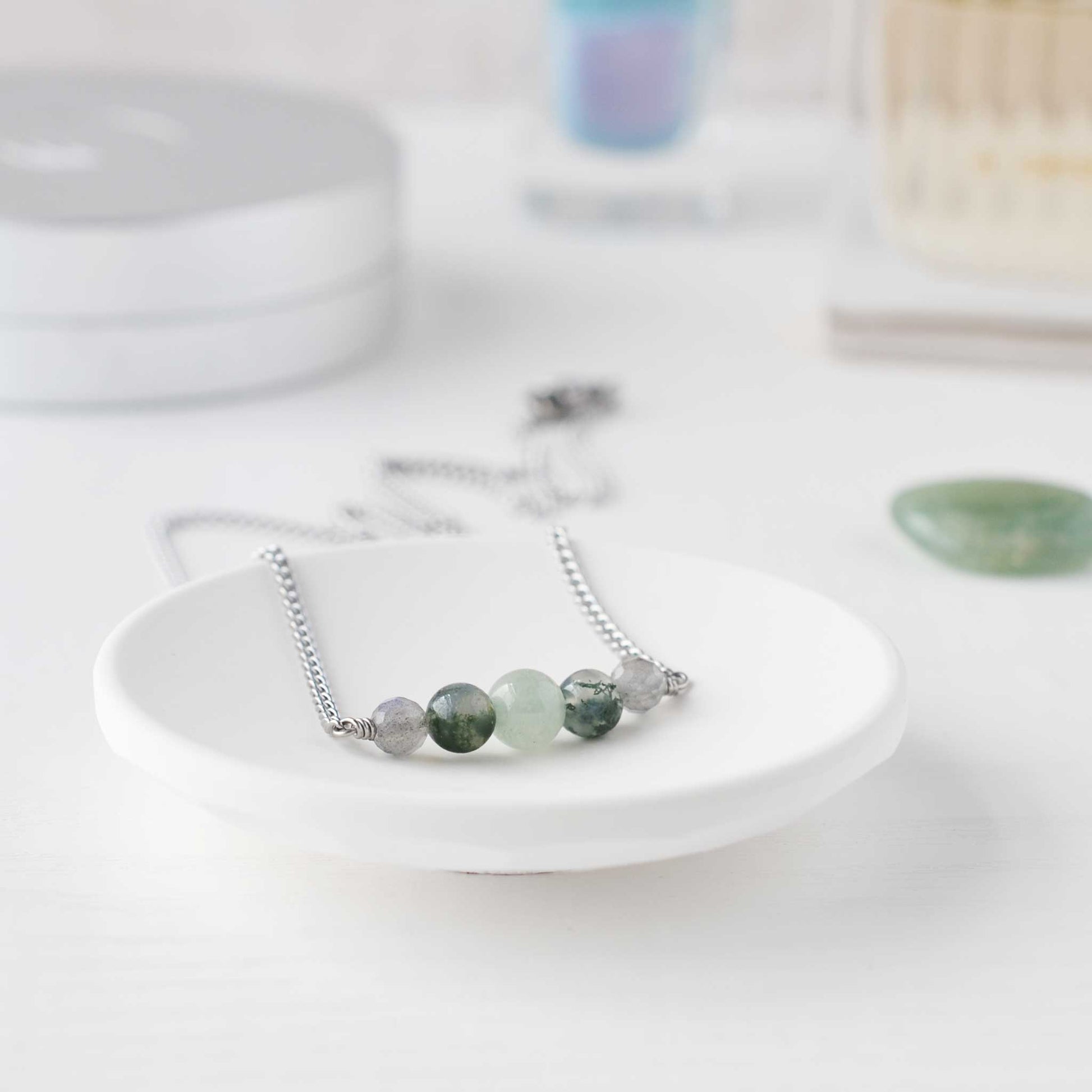 Green gemstone bead necklace in trinket dish on dressing table