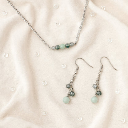Necklace and earrings with green beads on a beige fabric background
