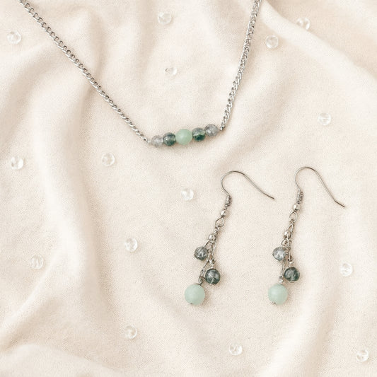 Necklace and earrings with green beads on a beige fabric background