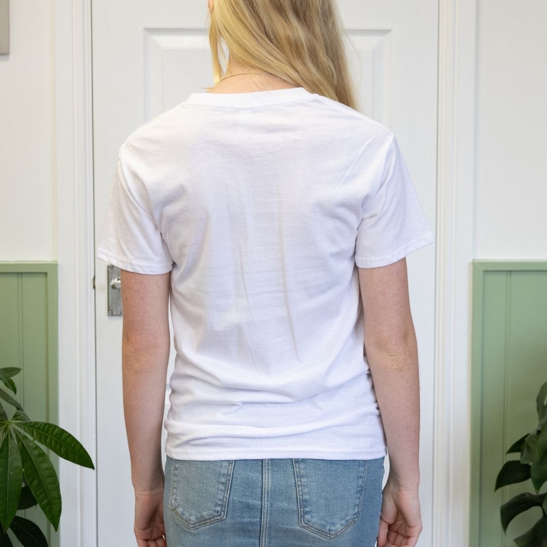 Person wearing a plain white t-shirt in front of a white door.